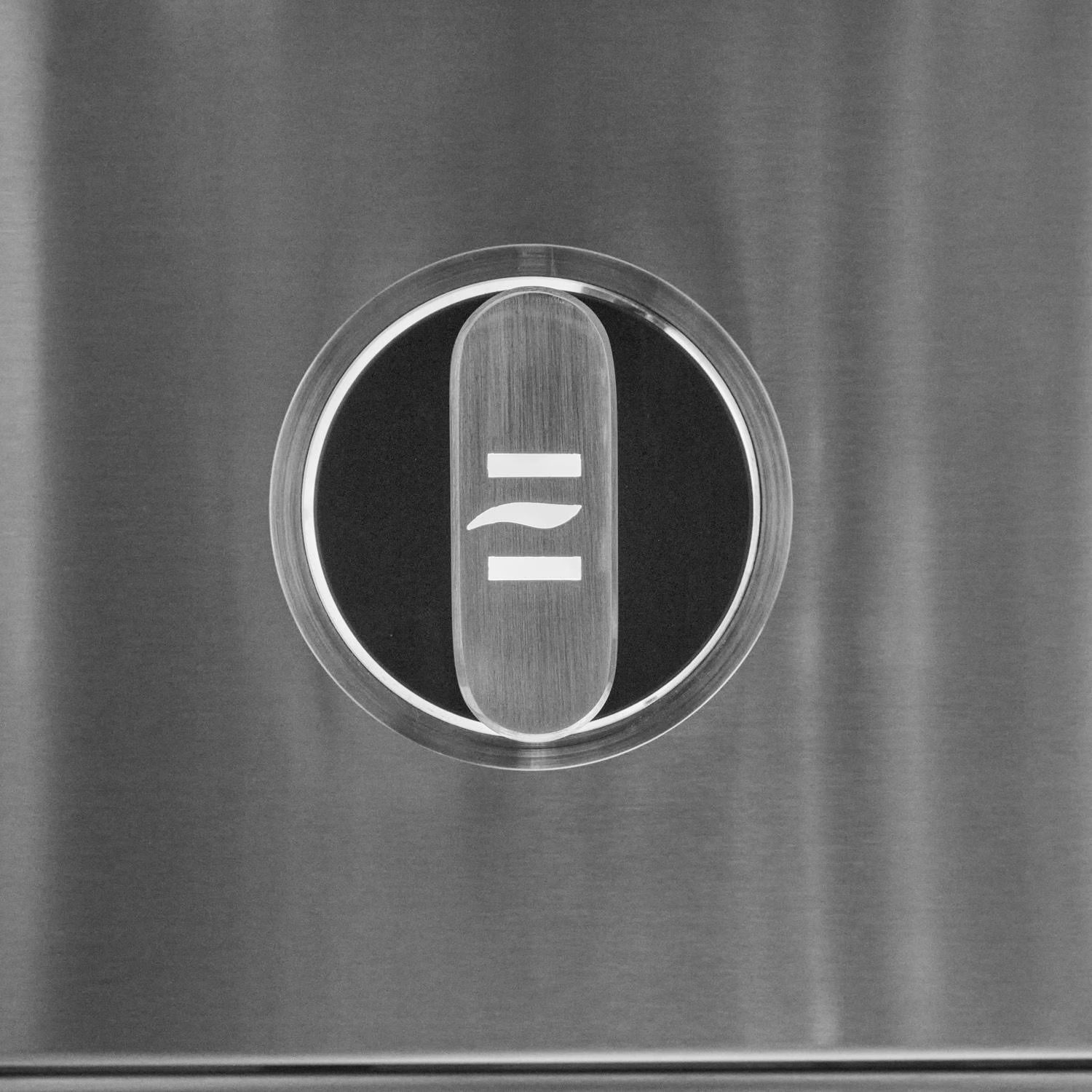 Close-up of an illuminated stainless steel grill control knob with a stylized emblem on a brushed control panel