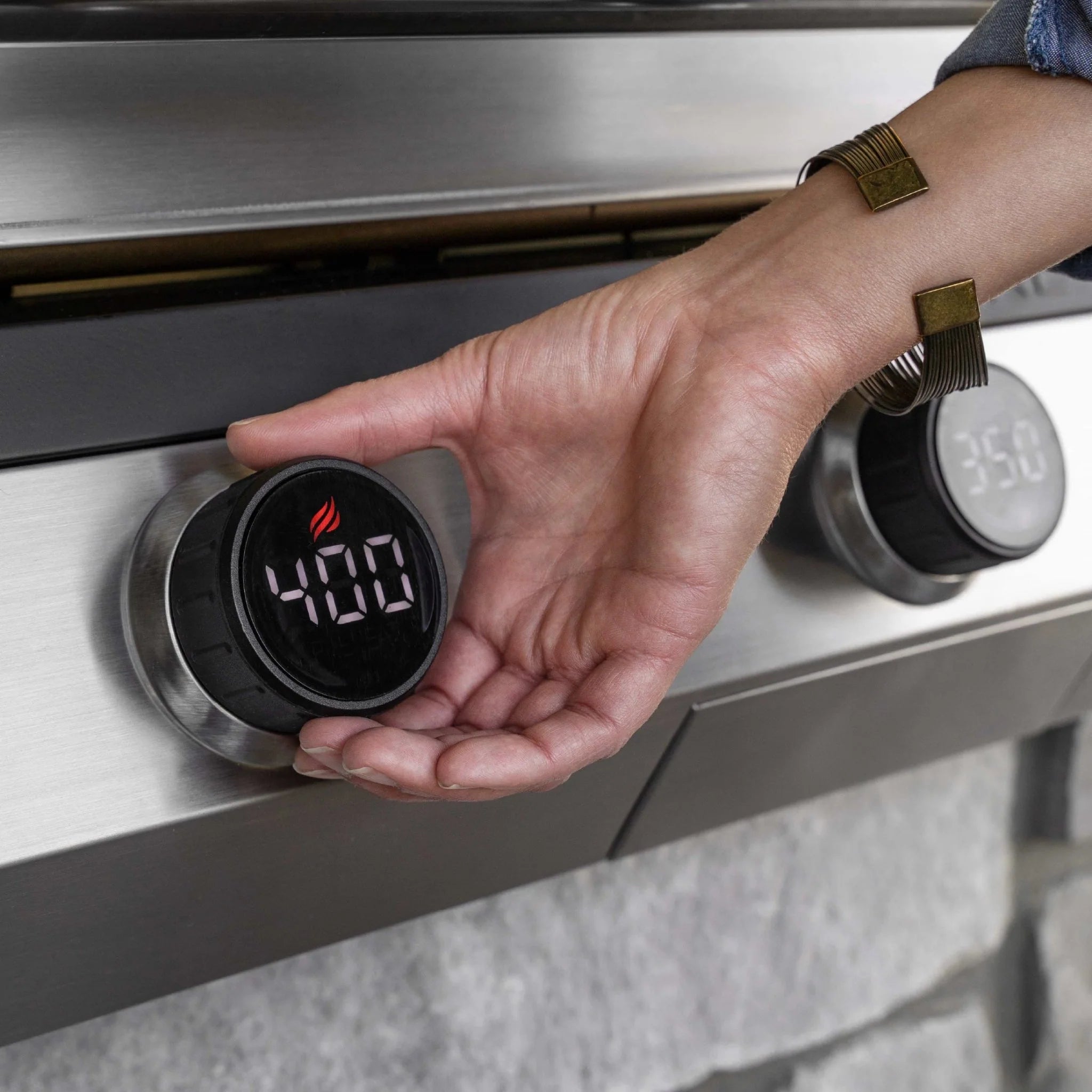 Close-up of a hand adjusting the LED digital temperature control knob to 400 degrees on a Blackstone electric drop-in griddle