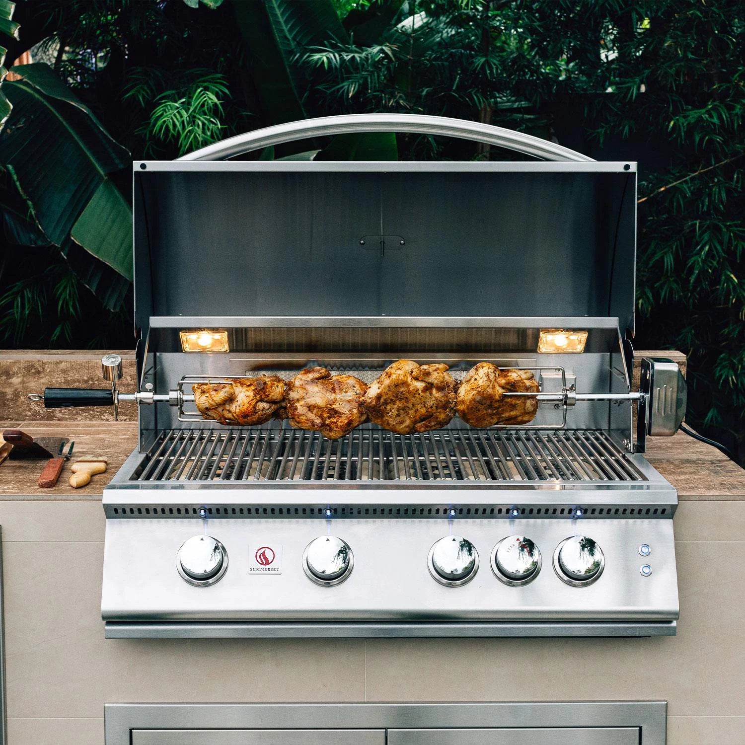 Summerset built-in gas grill with hood open roasting whole chickens on the rotisserie in an outdoor kitchen