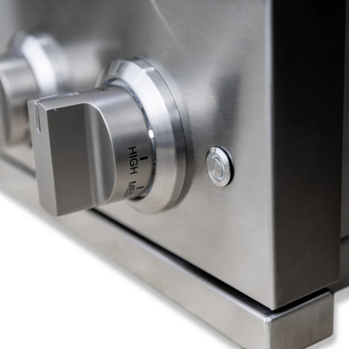 Close-up of a side burner's stainless steel control knob and ignition button on the control panel