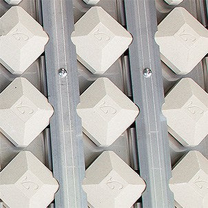 Close-up of white ceramic briquettes beneath the cooking grates of an Alfresco built-in gas grill