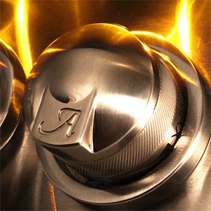 Close-up of an illuminated stainless steel control knob with the Alfresco logo on a built-in gas grill