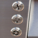Close-up of three stainless steel ignition, light and rotisserie control buttons on an Alfresco built-in gas grill