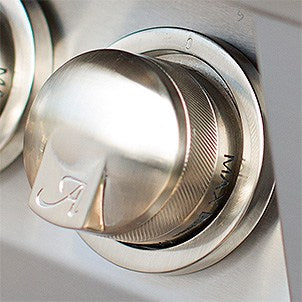 Close-up of a polished stainless steel control knob with an Alfresco logo on a built-in gas grill control panel