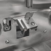 Close-up inside a grill firebox showing the ceramic flame-thrower ignition electrode and a stainless steel burner mounting bracket near a burner port