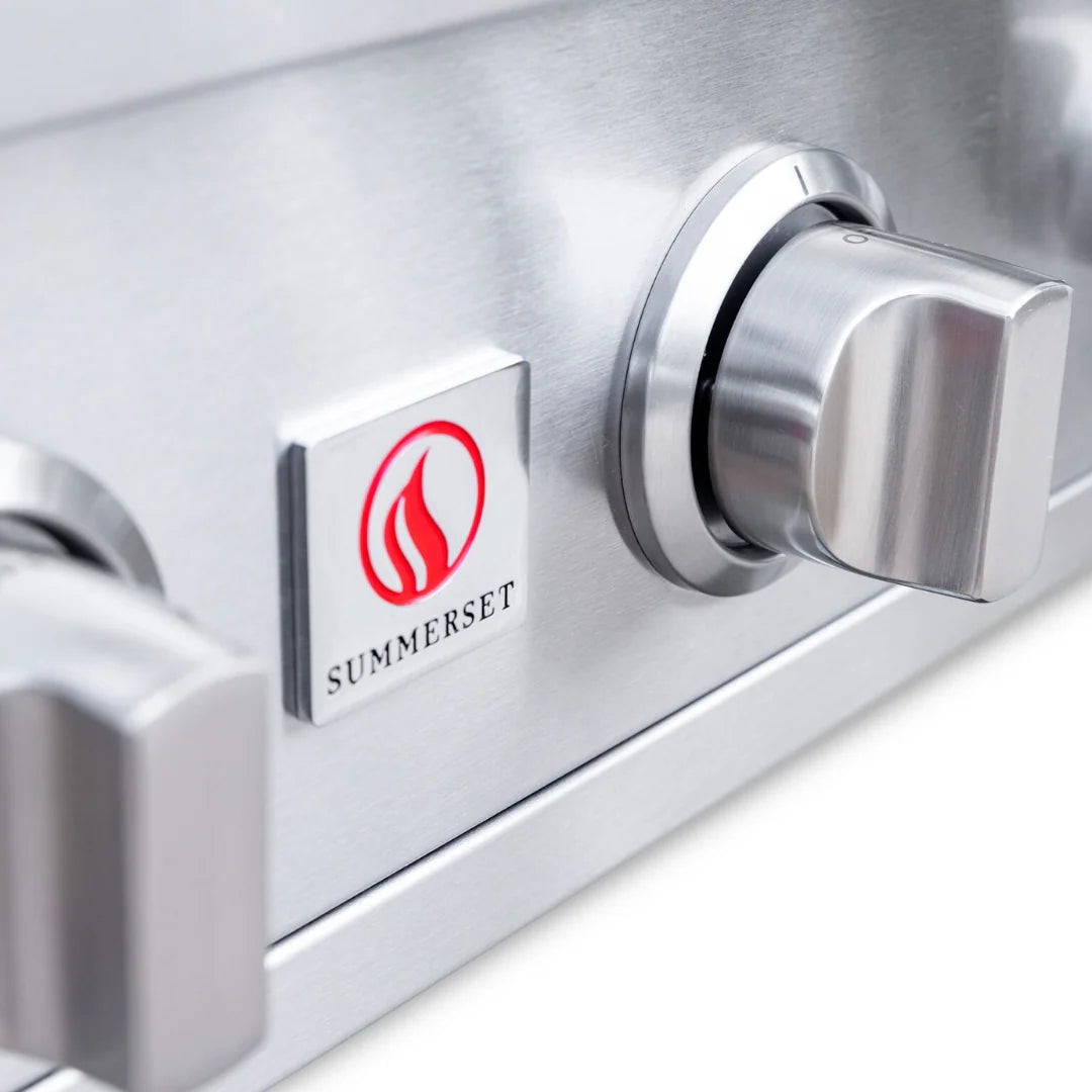Close-up of the control panel with the Summerset flame logo badge and a knob of a built-in gas grill