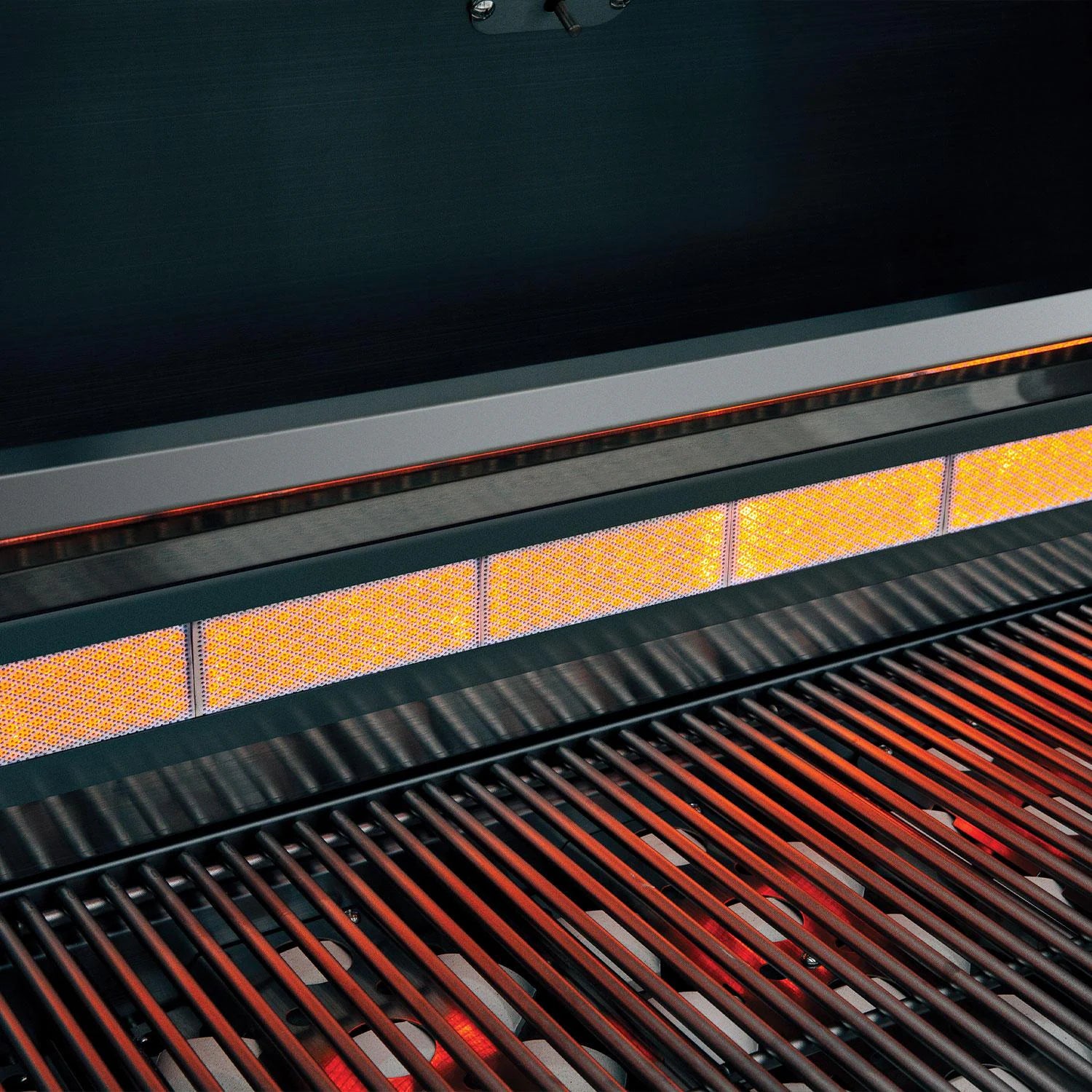 Glowing infrared rear rotisserie burner and red-hot cooking grates inside a Summerset built-in gas grill