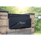 Black Alfresco vinyl cover with the white Alfresco script fitted over a burner set into an outdoor kitchen counter, photographed outdoors with sunlight behind