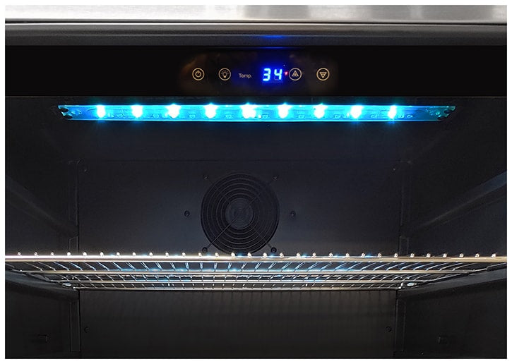 Illuminated interior of an Artisan outdoor refrigerator with blue LED lighting, a digital temperature display and a shelf
