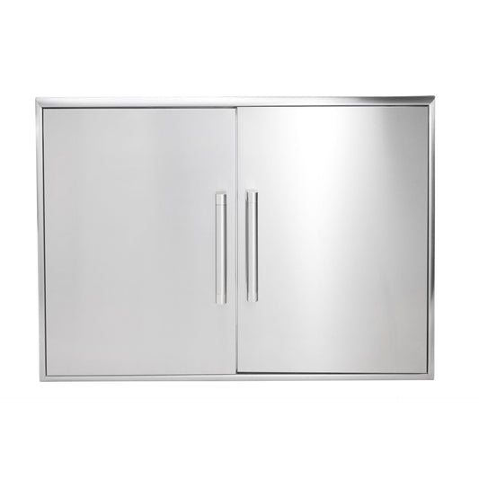 A stainless steel Coyote double-door outdoor kitchen access cabinet with two vertical tubular bar handles meeting at the center and a beveled outer frame, shown front-on against a white background