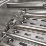A close-up detail thumbnail of the stainless steel slotted cooking grates of a built-in gas grill, shown at an angle
