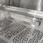 A close-up feature thumbnail of the perforated stainless steel warming rack mounted inside the upper section of a built-in gas grill