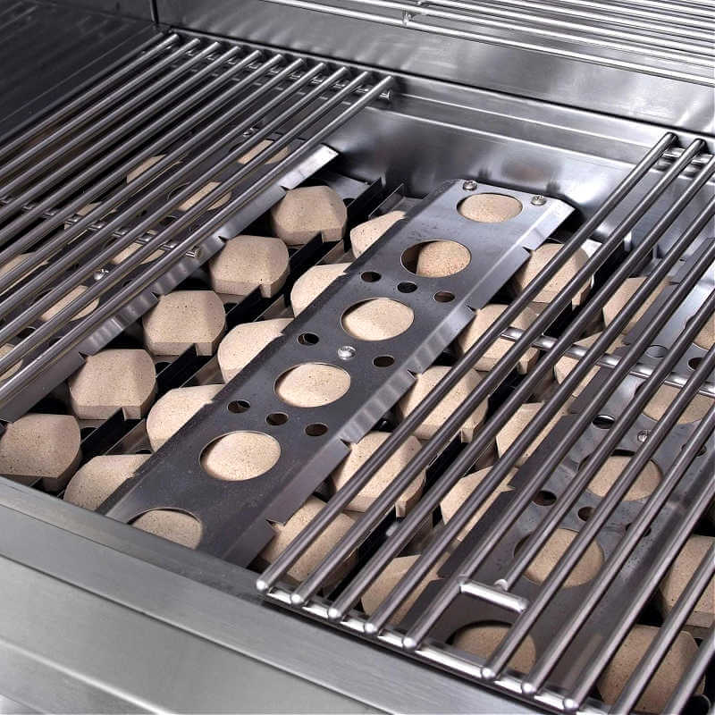 Close-up inside an RCS Premier grill firebox showing the tan ceramic briquettes seated in their metal trays beneath the stainless steel cooking grates