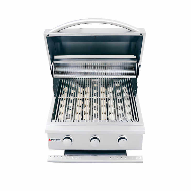 Front view of an RCS Premier 26-inch three-burner built-in stainless steel gas grill with the lid open, showing the cooking grates with ceramic briquettes beneath, three control knobs and the Renaissance Cooking Systems logo, on a white background