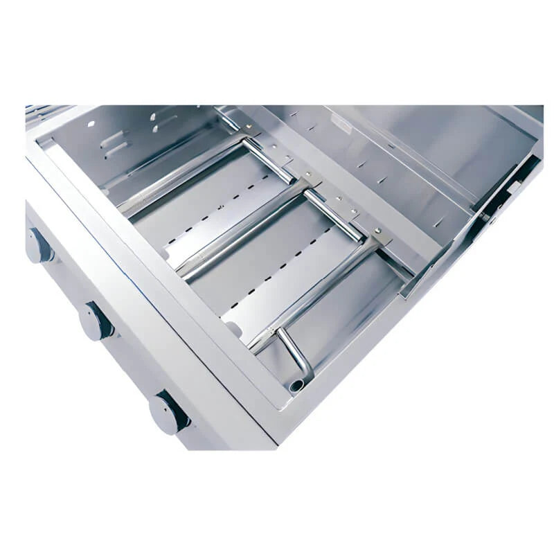 Angled close-up of an RCS Premier grill firebox interior with the grates and trays removed, showing the stainless steel tube burners mounted across the floor and the control knobs along the front