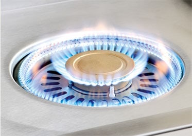 Alfresco 24-inch Versa Power cooker with both burners lit for full 65,000 BTU output around the brass center cap, AIPGVP