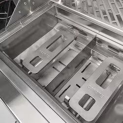 Interior view of a stainless steel grill showing the burner channels and removable warming rack