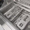 Interior view of a stainless steel grill showing the burner channels and removable warming rack