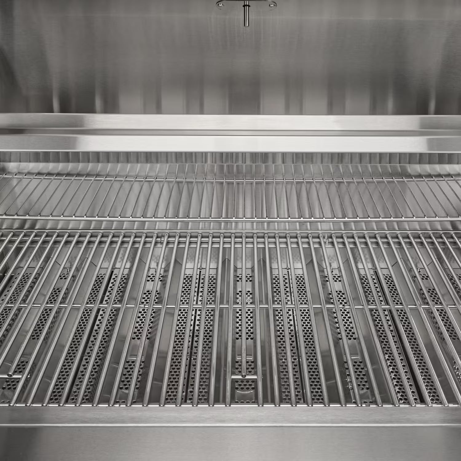Interior view of a grill showing the stainless steel cooking grates above the heat tents and burners