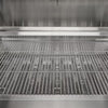 Interior view of a grill showing the stainless steel cooking grates above the heat tents and burners