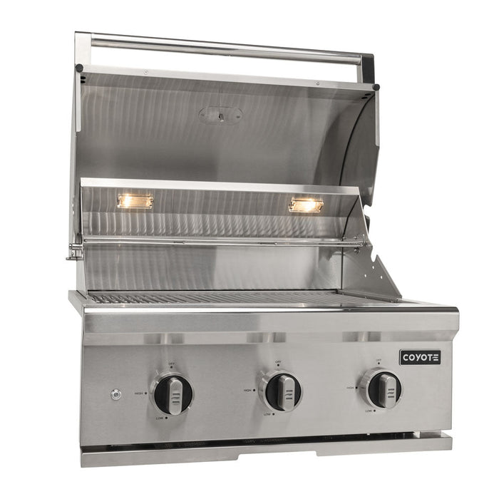 A stainless steel Coyote 30-inch C-Series built-in gas grill shown front-on with the lid open, revealing the cooking grates and two interior halogen lights, three control knobs on the front, and the Coyote logo, against a white background