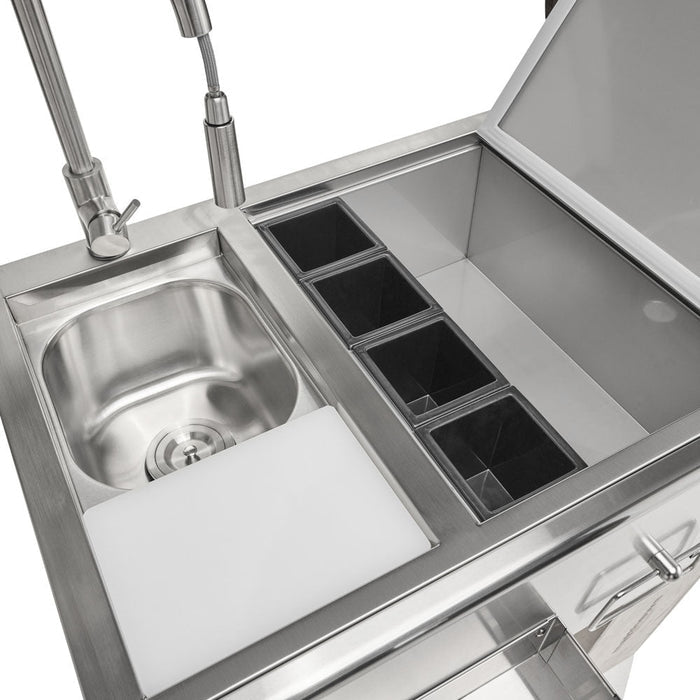 A close-up angled view of the top of the Coyote 30-inch refreshment center, showing the sink basin with cutting board, the gooseneck faucet, a row of stainless garnish compartments, and the open ice-bin lid, against a white background
