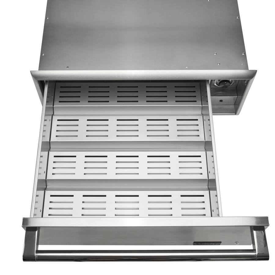 A stainless steel built-in outdoor warming drawer pulled open and viewed from above, showing the slotted vented rack surfaces inside, against a white background
