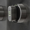 Close-up of a stainless steel grill control knob with illuminated green position markings, on a brushed metal control panel