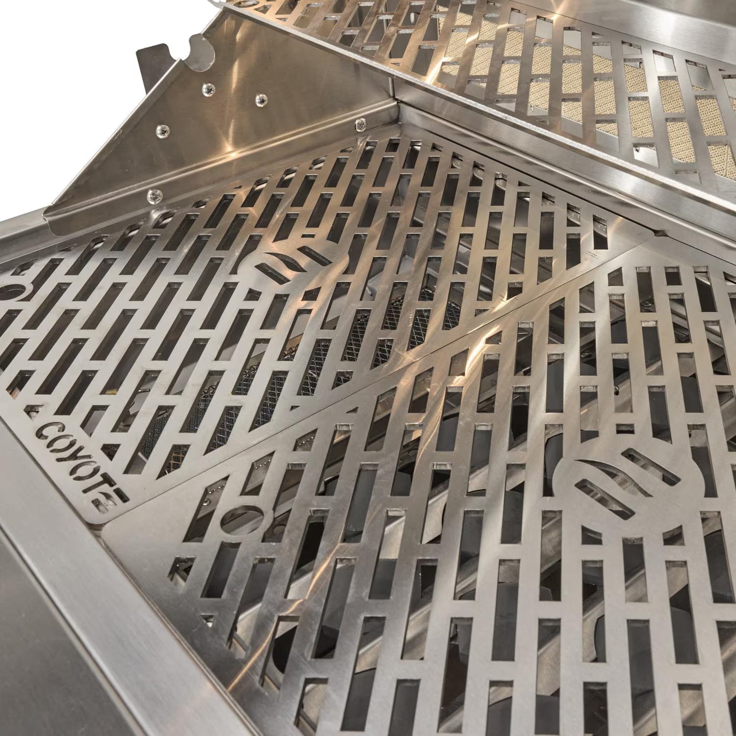Close-up of the Coyote-branded stainless steel cooking grates inside a grill, with the warming rack visible above