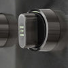 Close-up of a stainless steel grill control knob with illuminated green position markings, on a brushed metal control panel