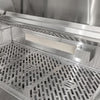 Interior of an open Coyote stainless steel grill showing the rear infrared burner with its mesh screen mounted at the back of the firebox, above the Coyote-branded cooking grates