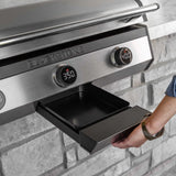 Person pulling out the front-access grease drawer on a Blackstone electric drop-in griddle built into a stone island