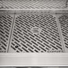 Top-down close-up of the Coyote-branded stainless steel cooking grates with the embossed Coyote logo, and the warming rack visible above