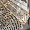 Close-up of the Coyote-branded stainless steel cooking grates and a heat diffuser plate inside a grill