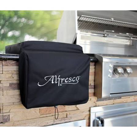 Black Alfresco vinyl cover with the white Alfresco script fitted over a side burner in a stone-faced outdoor kitchen island, with a stainless Alfresco grill and its open hood alongside