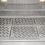 A close-up feature image of the interior of a grill showing tiered stainless steel cooking grates with a diamond mesh pattern