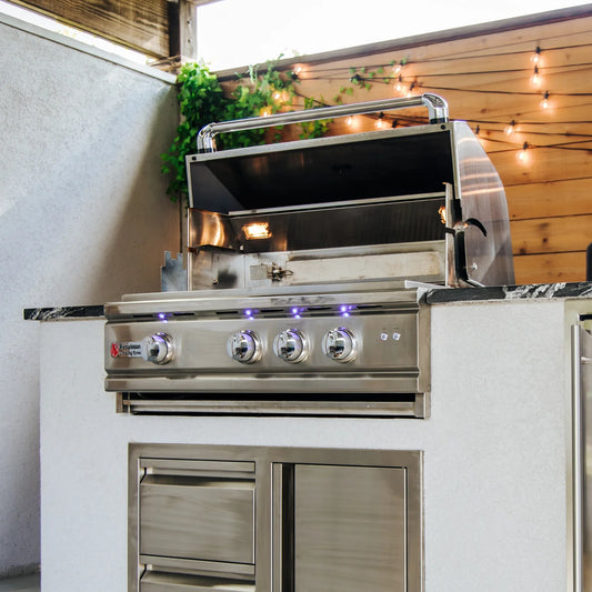 RCS stainless steel built-in gas grill with open lid and blue LED control knobs in a white outdoor kitchen island