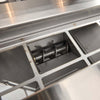 Close-up inside a stainless steel pellet grill hopper showing the metal auger screw at the bottom of the rectangular pellet feed opening