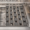Interior of a Coyote grill firebox showing rows of dark ceramic radiant briquettes seated in metal channels above the burners, with the Coyote-branded warming rack at the top