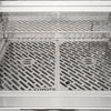 Interior front view of an open Coyote grill showing the Coyote-branded stainless steel cooking grates and the warming rack above