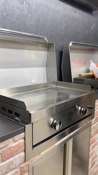 Stainless steel built-in flat-top griddle in a brick outdoor kitchen island